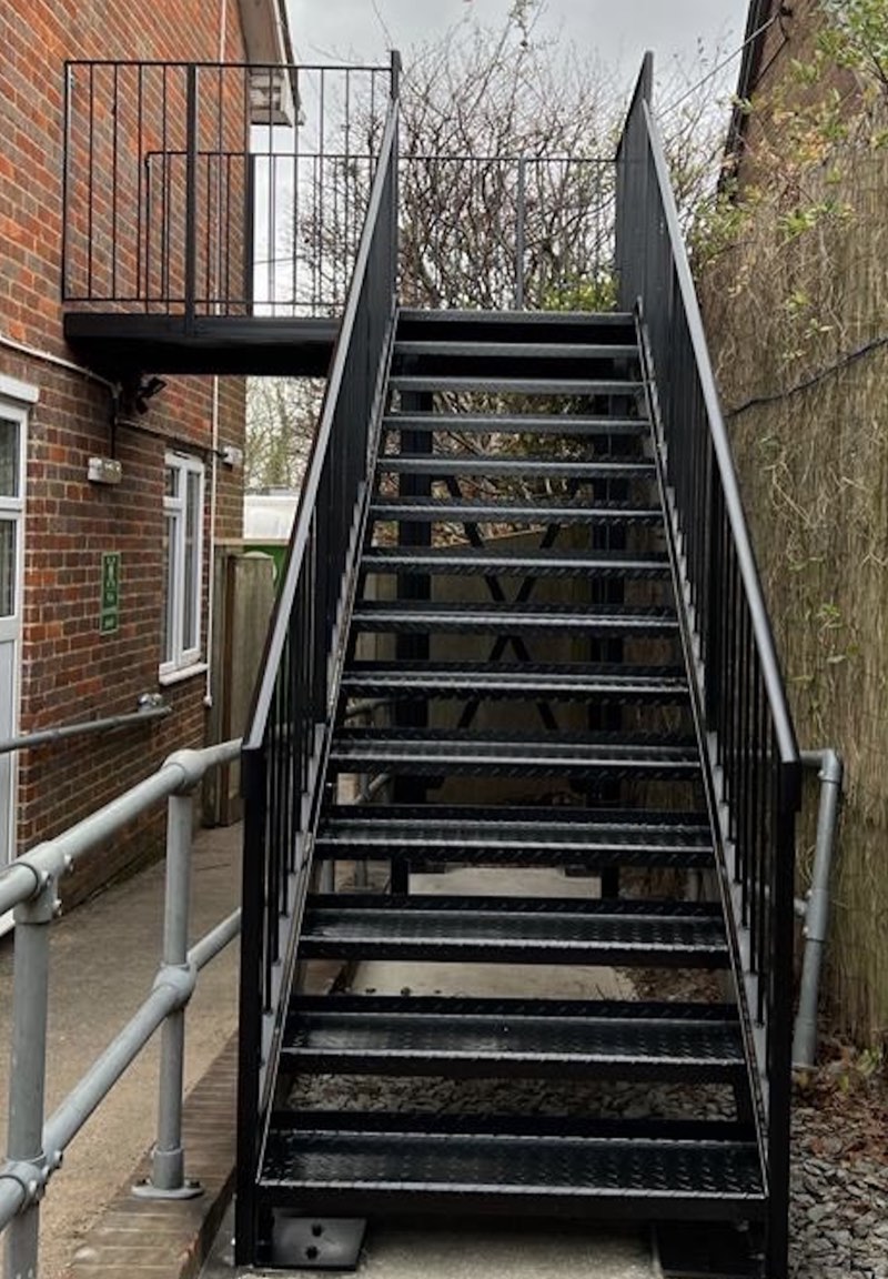 Black external staircase rising to a first-floor balcony