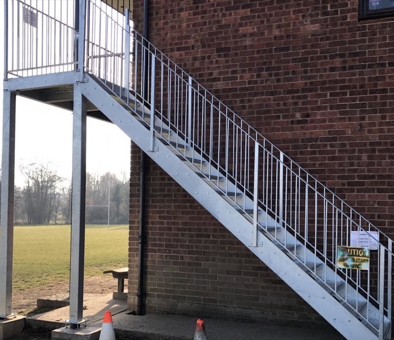 Galvanised straight staircase with an upper platform on a brick building