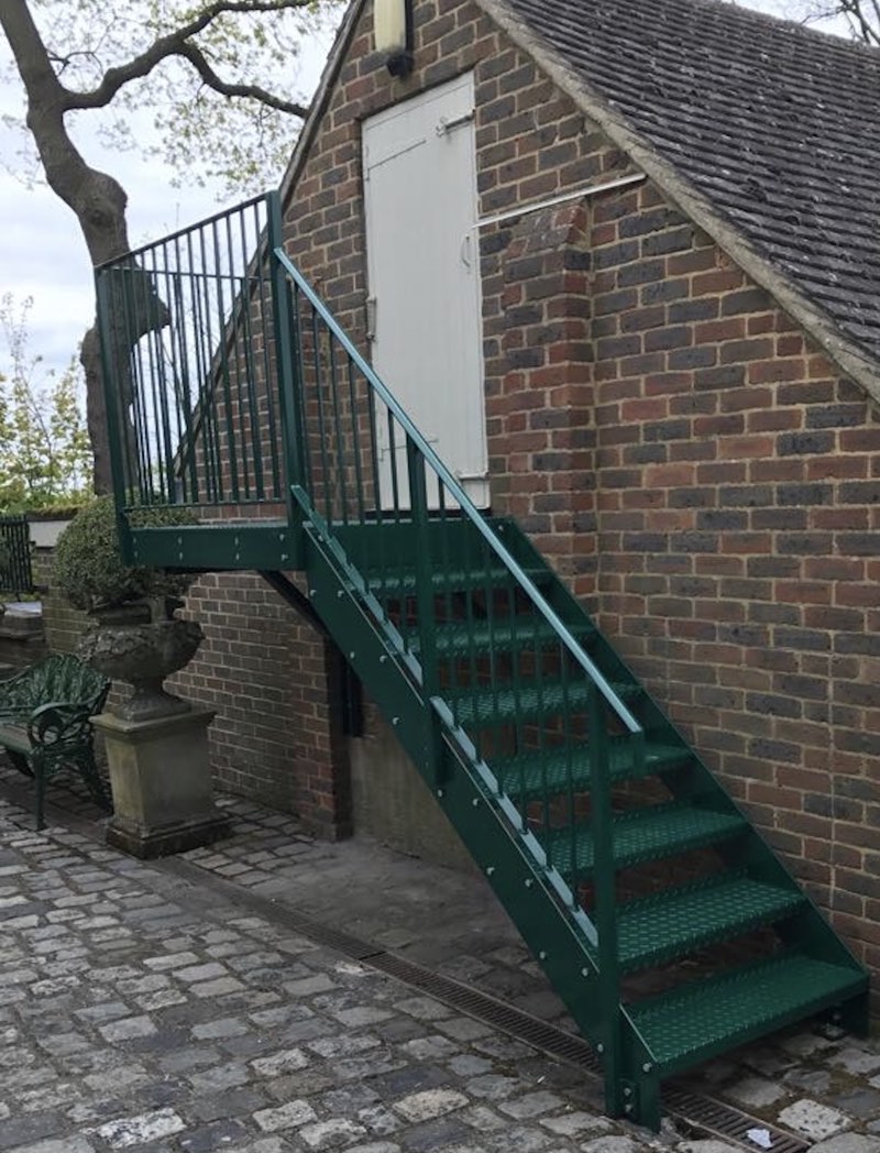 Green powder-coated straight garden staircase with a platform, fitted to a brick house