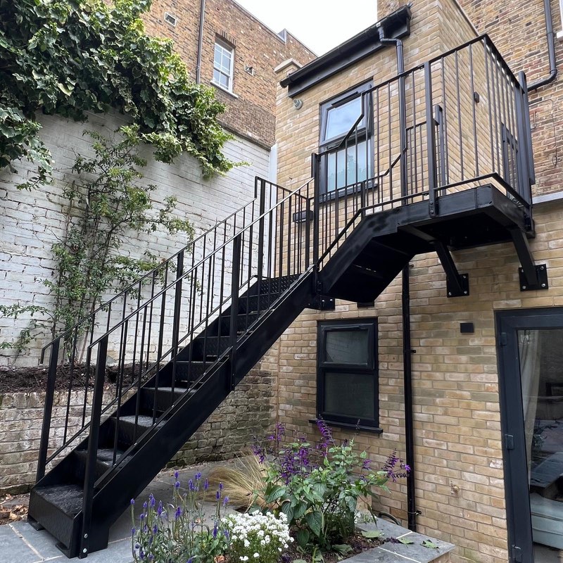 Black steel staircase and balcony on a London brick house with planting below